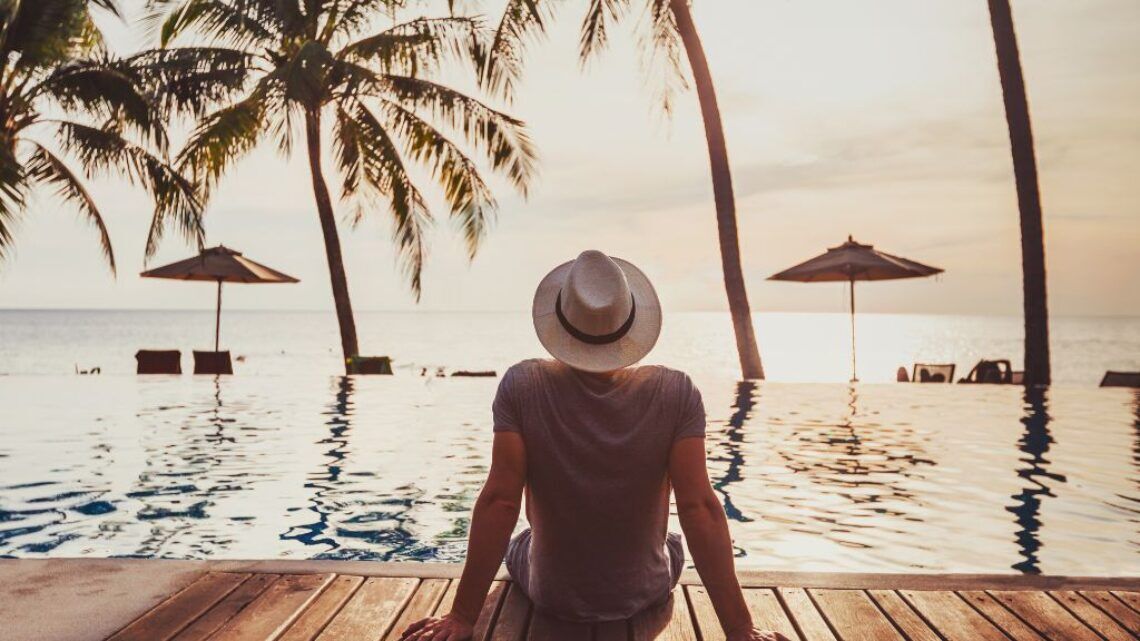 Consultant en portage salarial assis au bord d’une piscine face à la mer, profitant de vacances financées par des chèques-vacances